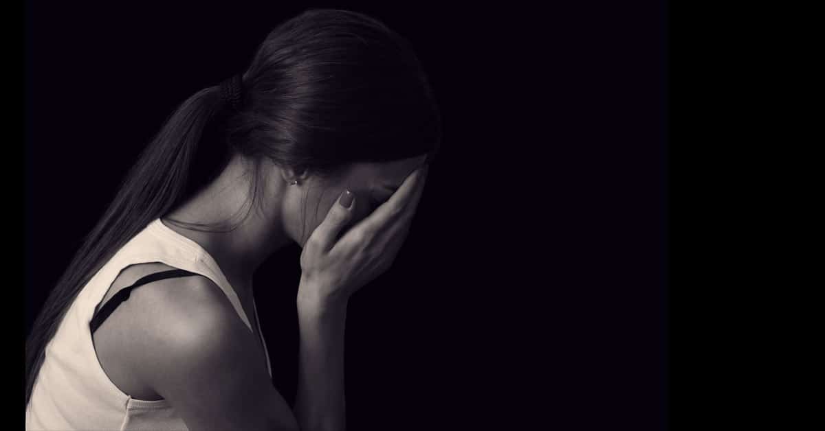 A regretful woman captured in a black and white photo, her hand resting on her face.