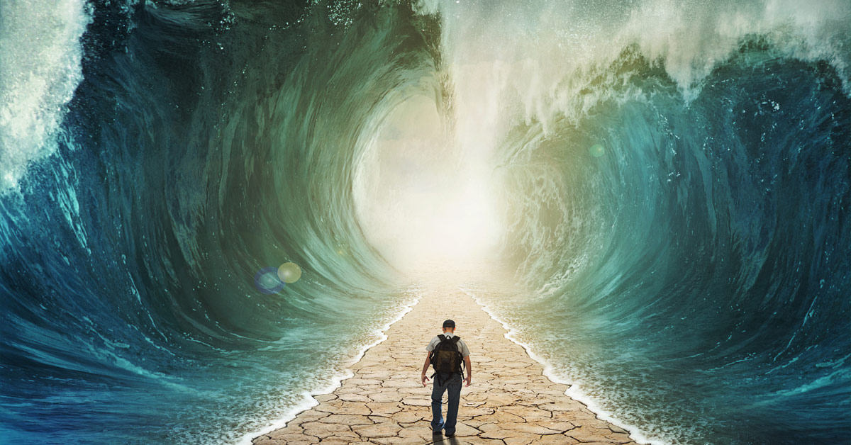 A man displays emotional intelligence as he stands before a powerful ocean wave.