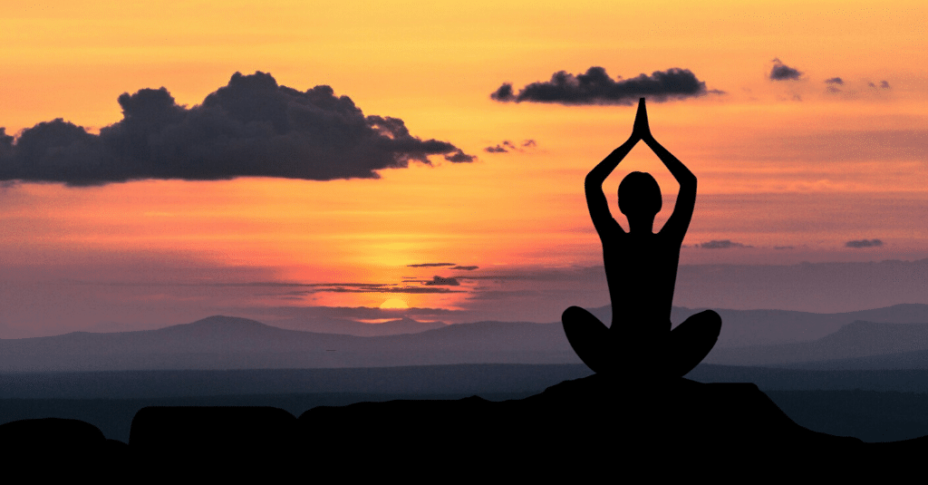 A person practicing yoga with a serene mountain backdrop, embodying zen habits.