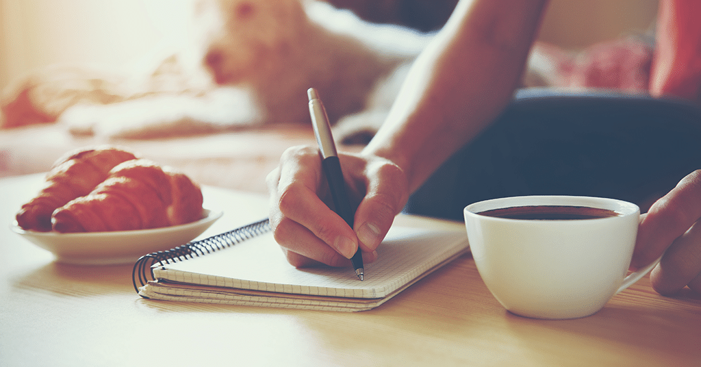 A woman using the 55x5 method while sipping coffee and diligently writing in a notebook.