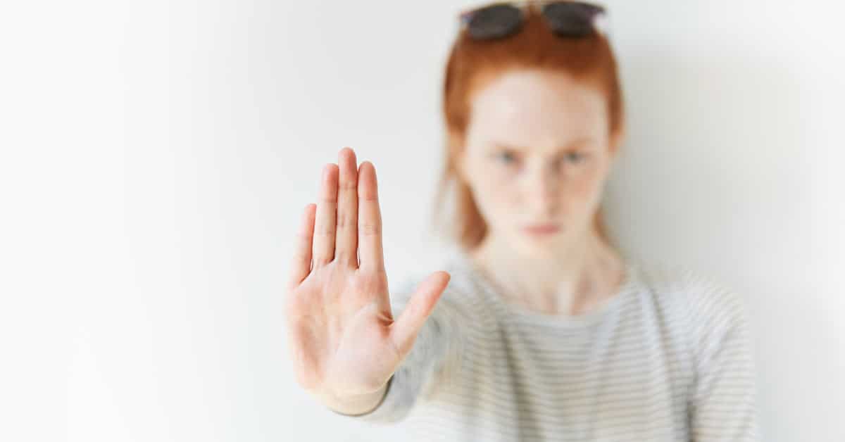 A attractive woman with red hair holding a stop sign.