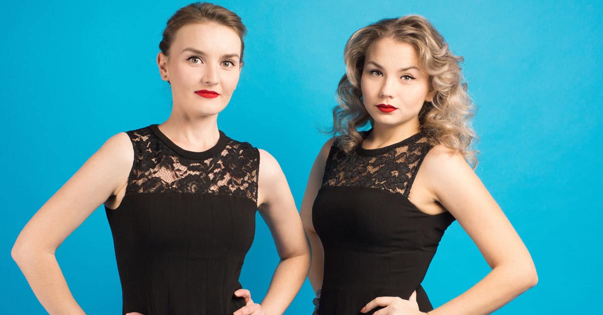Two women in black dresses posing for a coincidental photo.