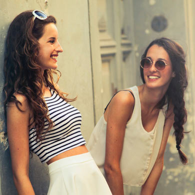 Two young women leaning against a wall, questioning their mistake.