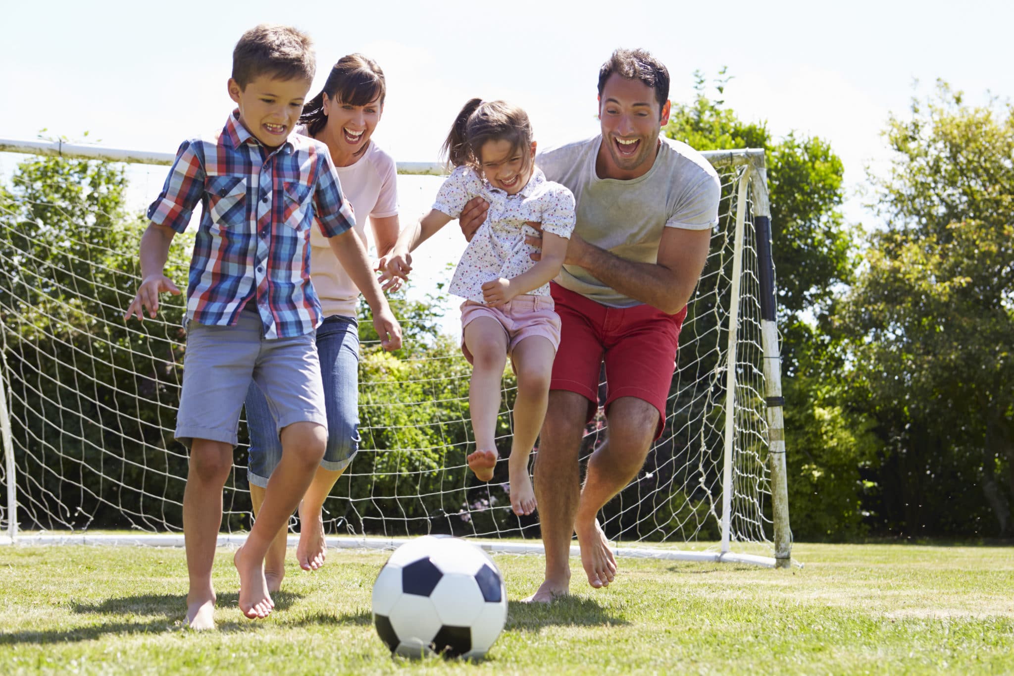 Family Playing Football In Garden Together