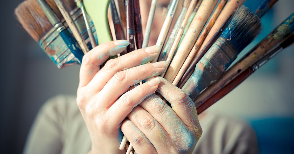 A woman using the law of attraction to hold a bunch of paint brushes.