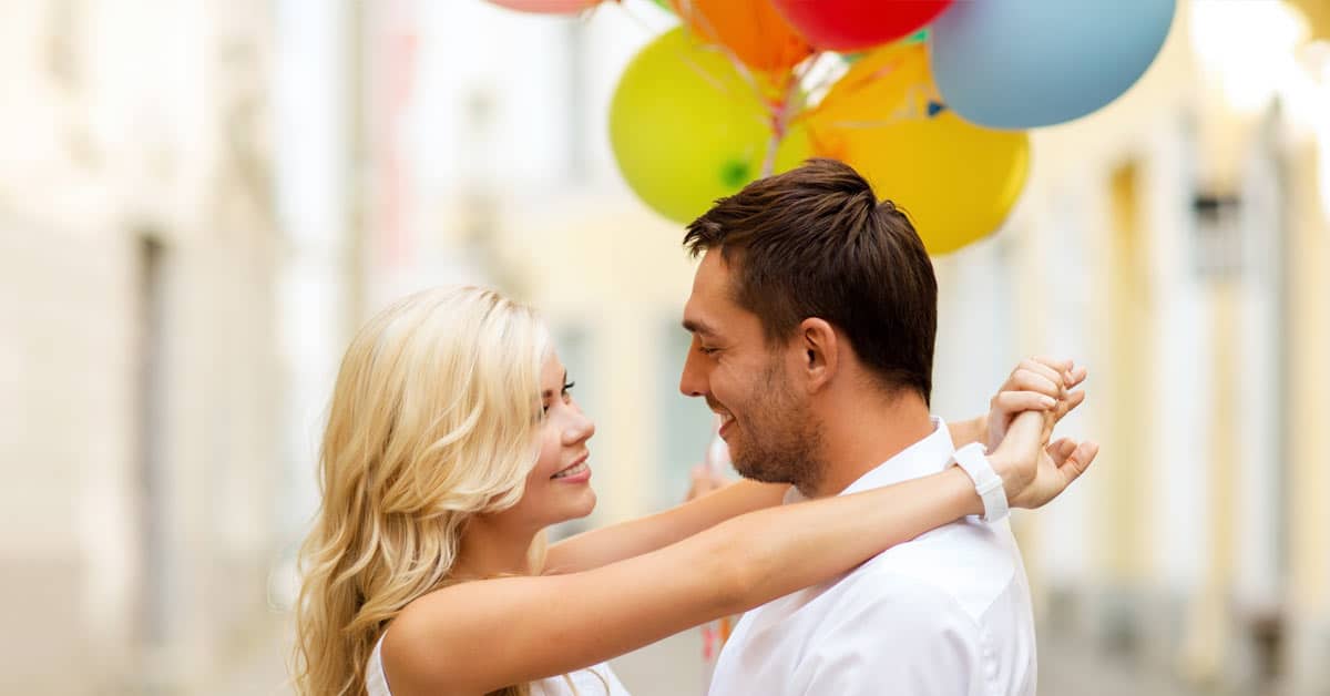 A couple dating, hugging while holding balloons.