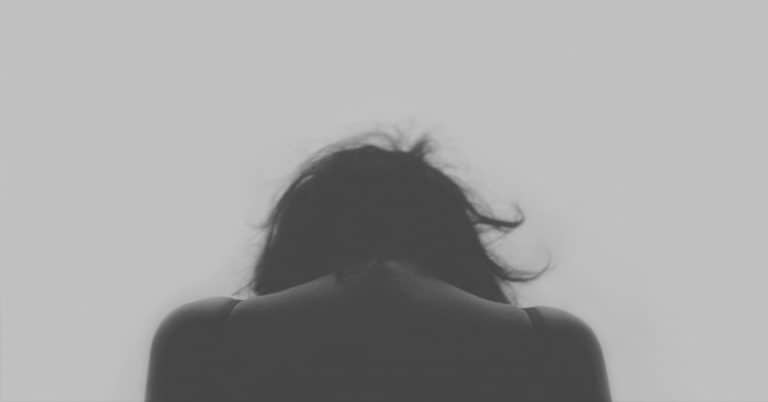 A monochrome image capturing a woman's back, conveying themes of depression.