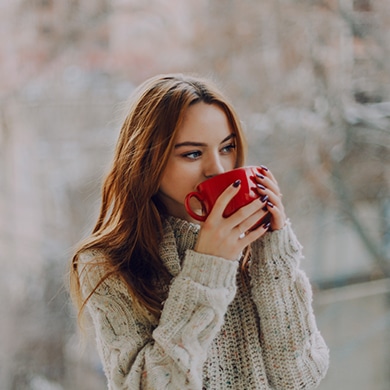 Pretty young lady drinking from a red mug