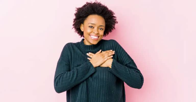 Black woman holding her heart, pink background