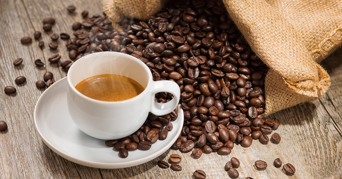 A cup of coffee with coffee beans on a wooden table, emphasizing morning routines.