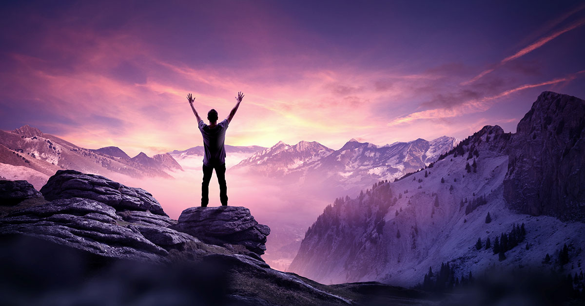 A man practicing self-improvement stands triumphantly on top of a mountain, raising his arms in celebration of his natural talent and following a practical guide.