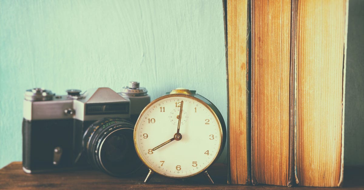 A clock, camera and books on a wooden table serving as spirit items.