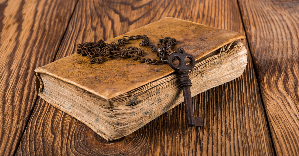 A wooden table with an old book and a key on top.