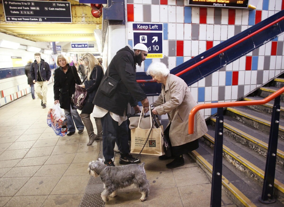 Hussain, a 34 year old Muslim, helps an elderly lady with her bags at the train station in London.