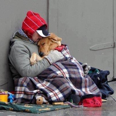 A homeless man and his dog keep each other warm.