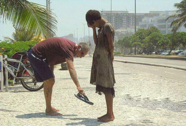 A man gives his shoes to a young, homeless girl in Rio de Janeiro.