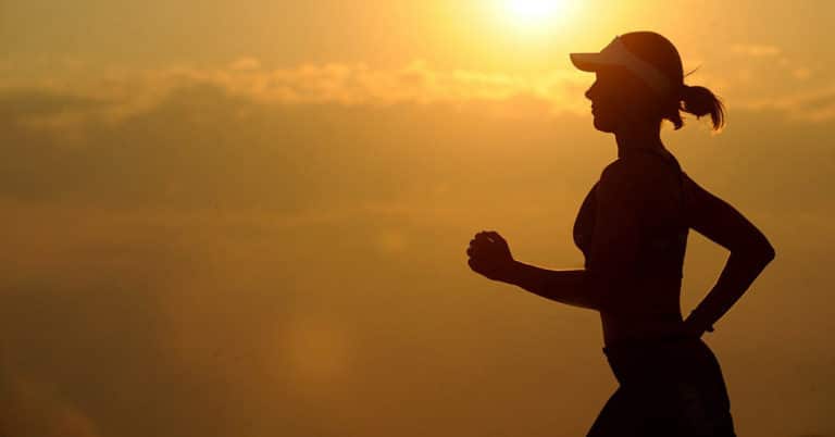 A silhouette of a woman jogging at sunset, promoting better health.