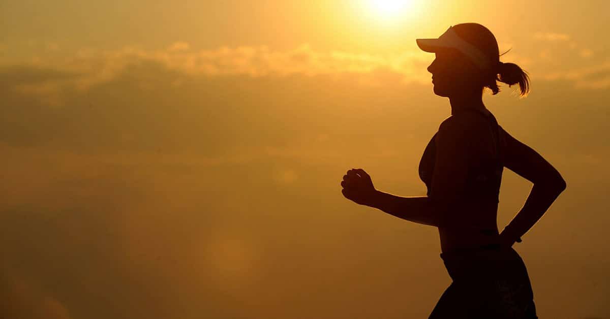 A silhouette of a woman jogging at sunset, promoting better health.